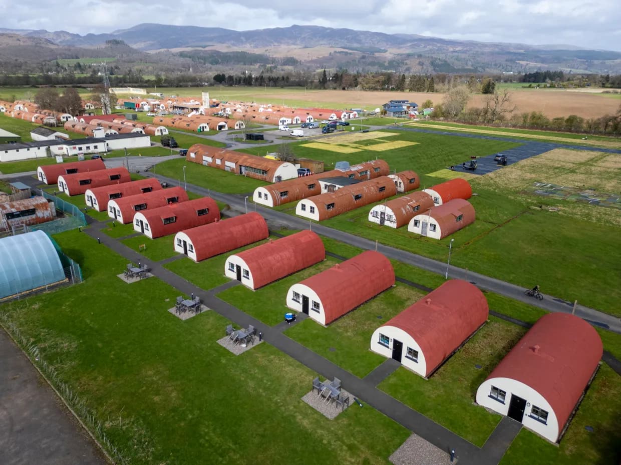 High-altitude drone view of Cultybraggan Camp showing dozens of red-roofed Nissen huts in a grid across the Perthshire landscape