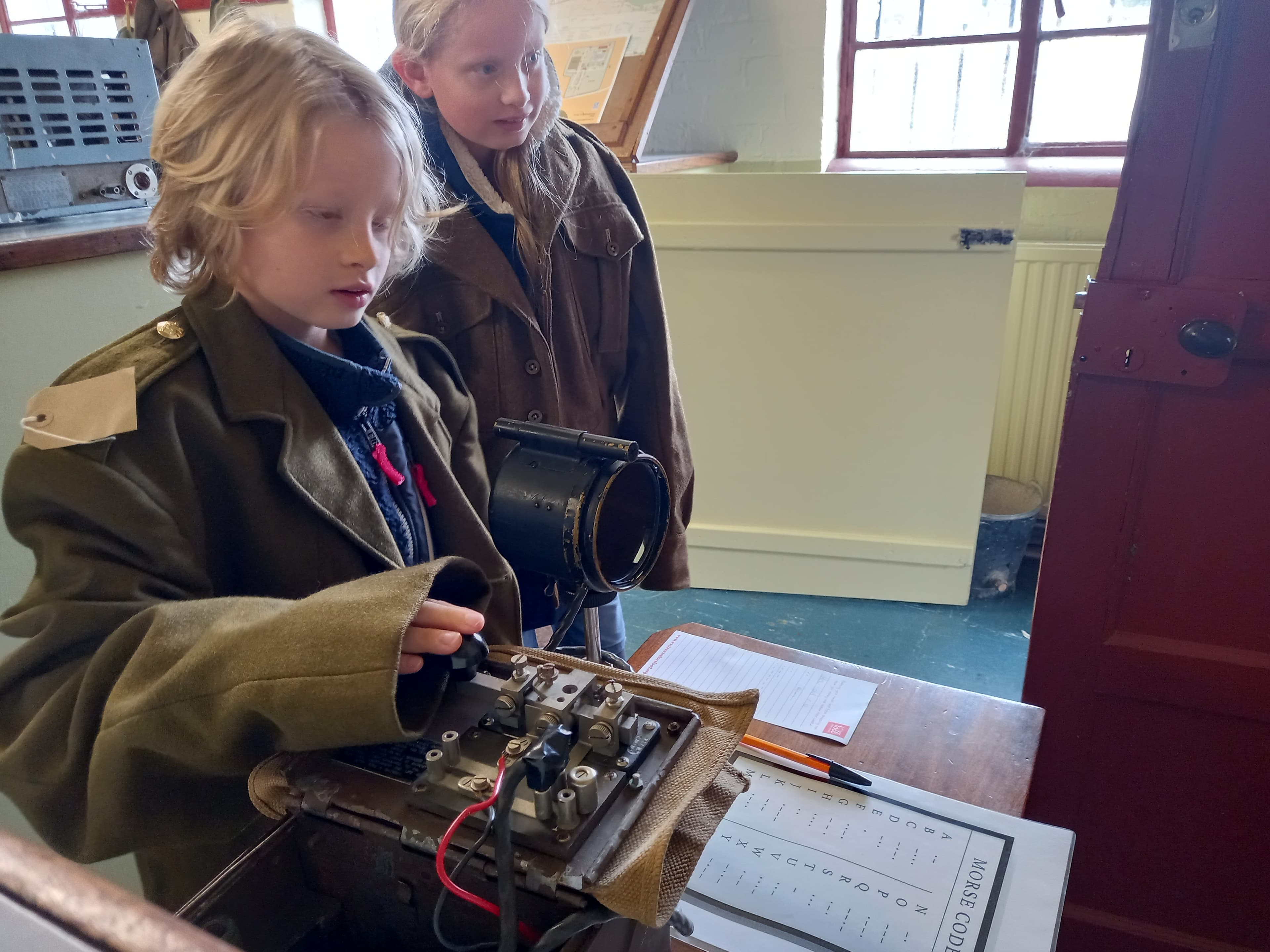 Children actively exploring wartime Morse code equipment inside a Nissen hut at Cultybraggan Camp — the kind of hands-on learning the museum supports